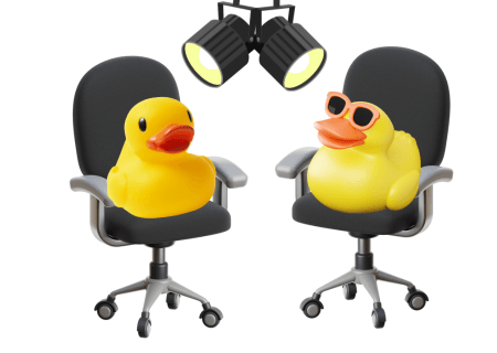 Yellow plastic duks, one with sun glasses on sitting on office style chairs with spotlights shining on them